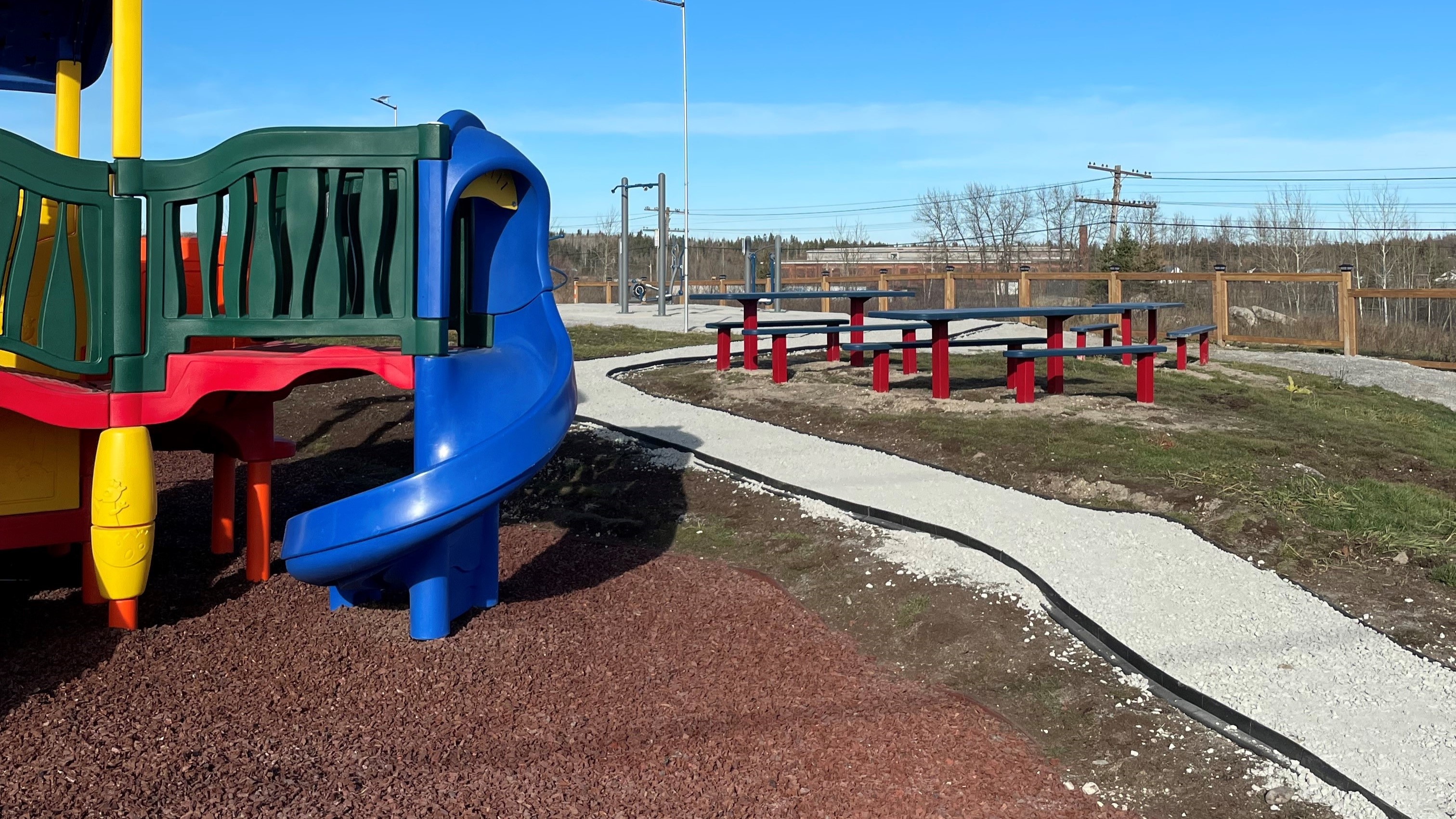 Image of a park, with a play structure in the foreground, and benches in the background. 